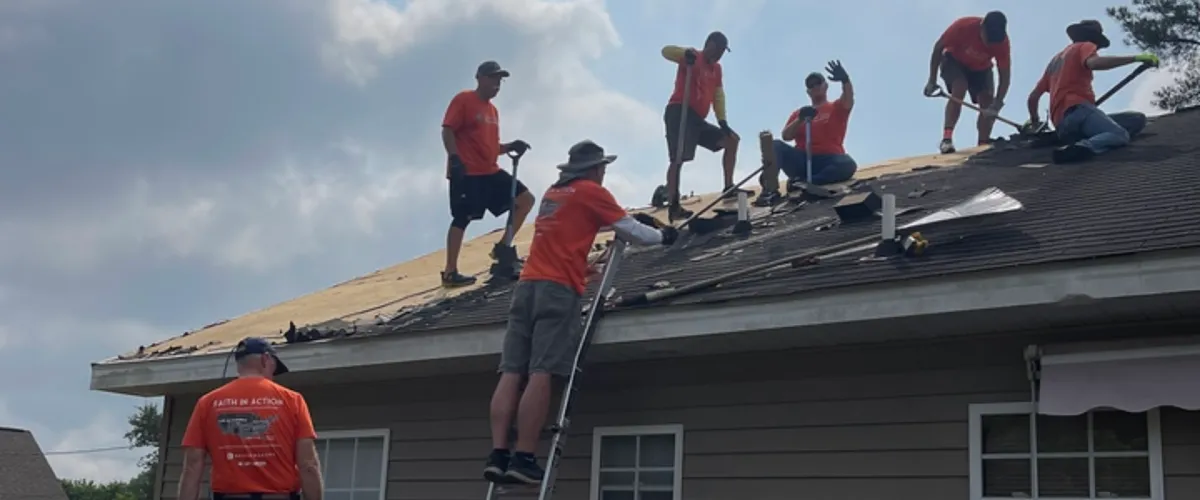 Group of Fuller Center volunteers in orange shirts repairing a rooftop as part of a critical home repair project in Delaware.