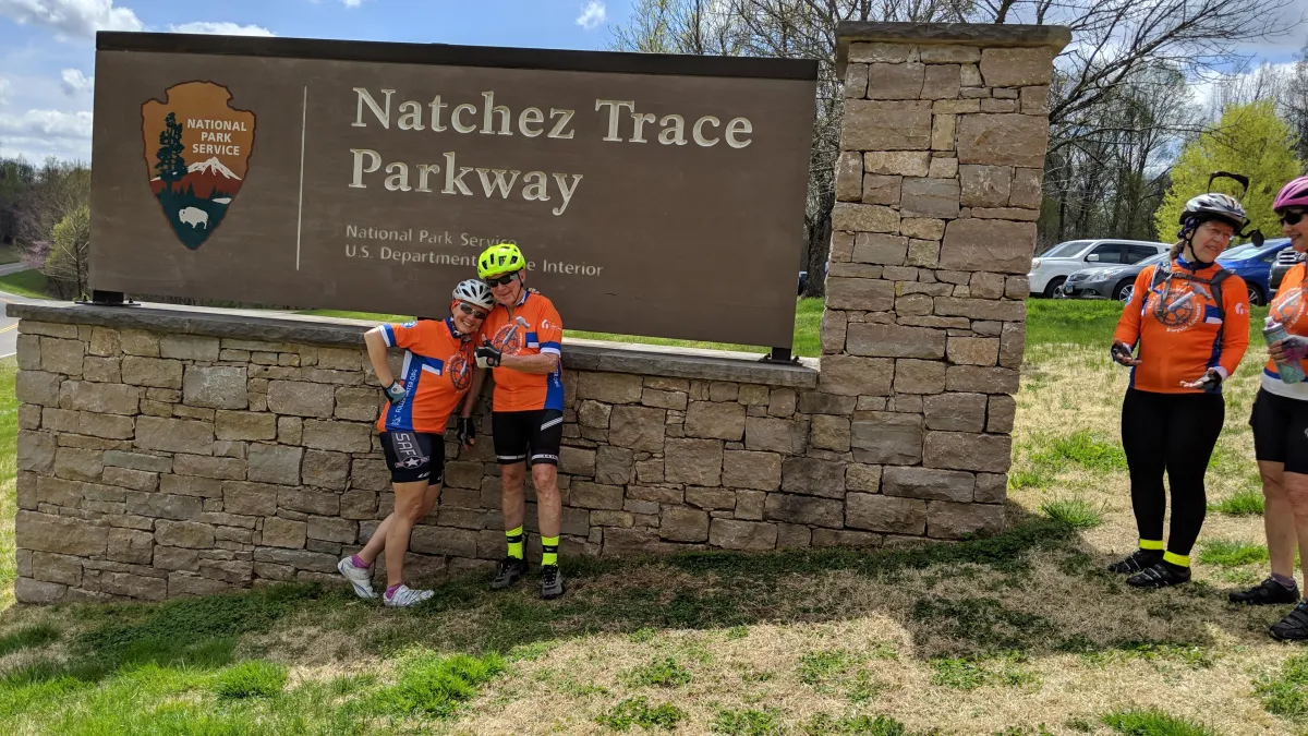 	Michele and Jay in orange jerseys at Natchez Trace sign