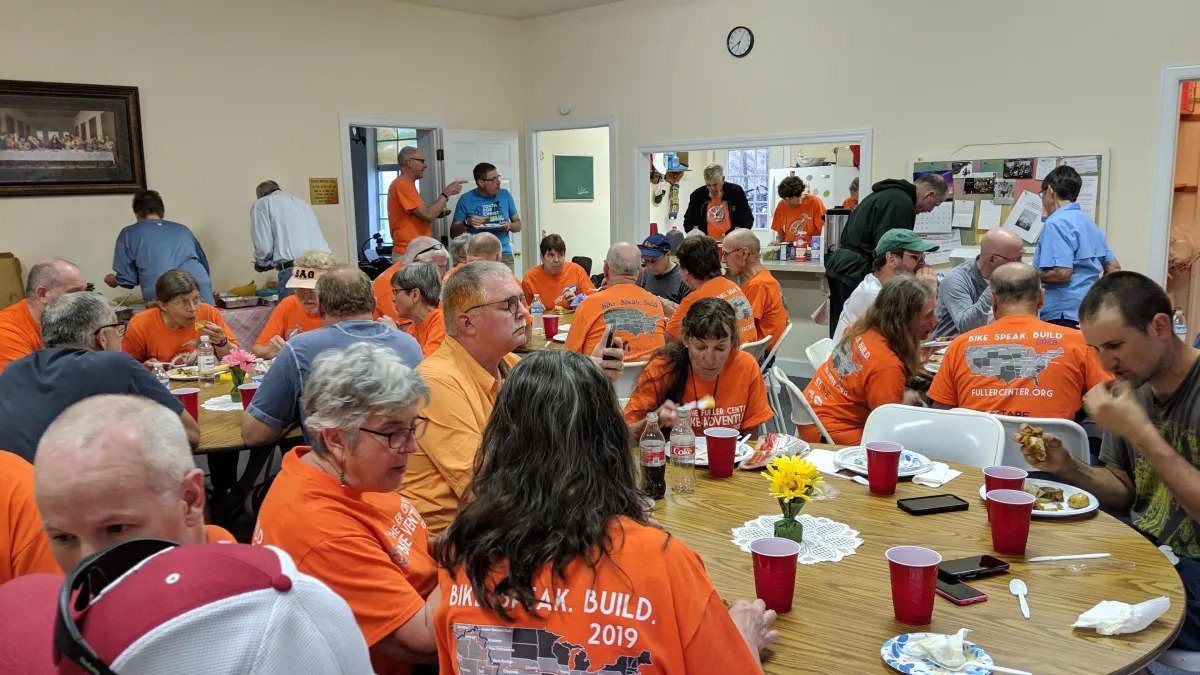 Volunteers and community partners preparing meals and setting up materials to support a Fuller Center repair project.