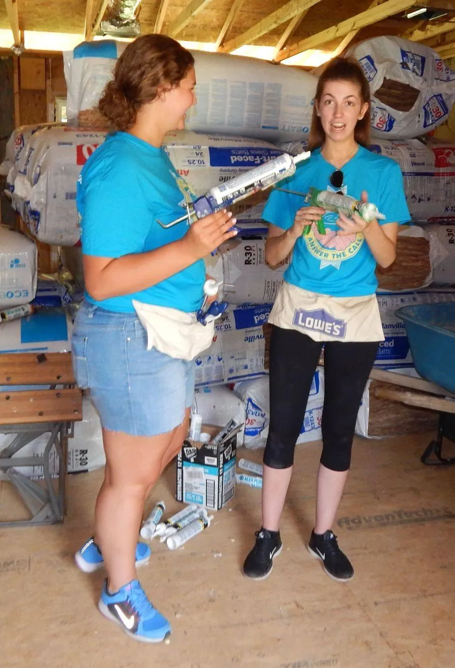 Two volunteers with caulking guns laughing during a build day