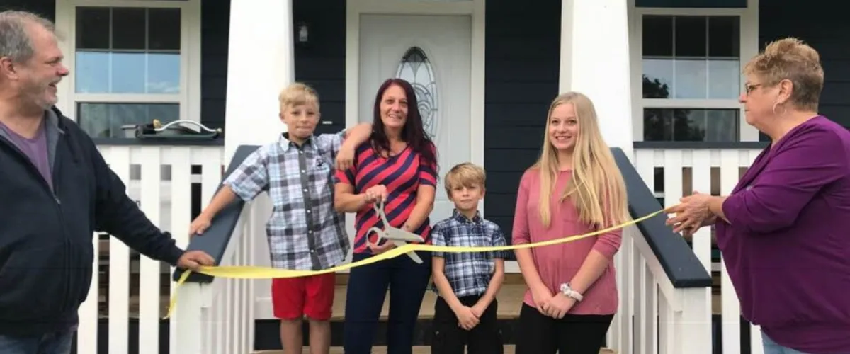 Volunteer and family cutting ribbon at a tiny house ceremony