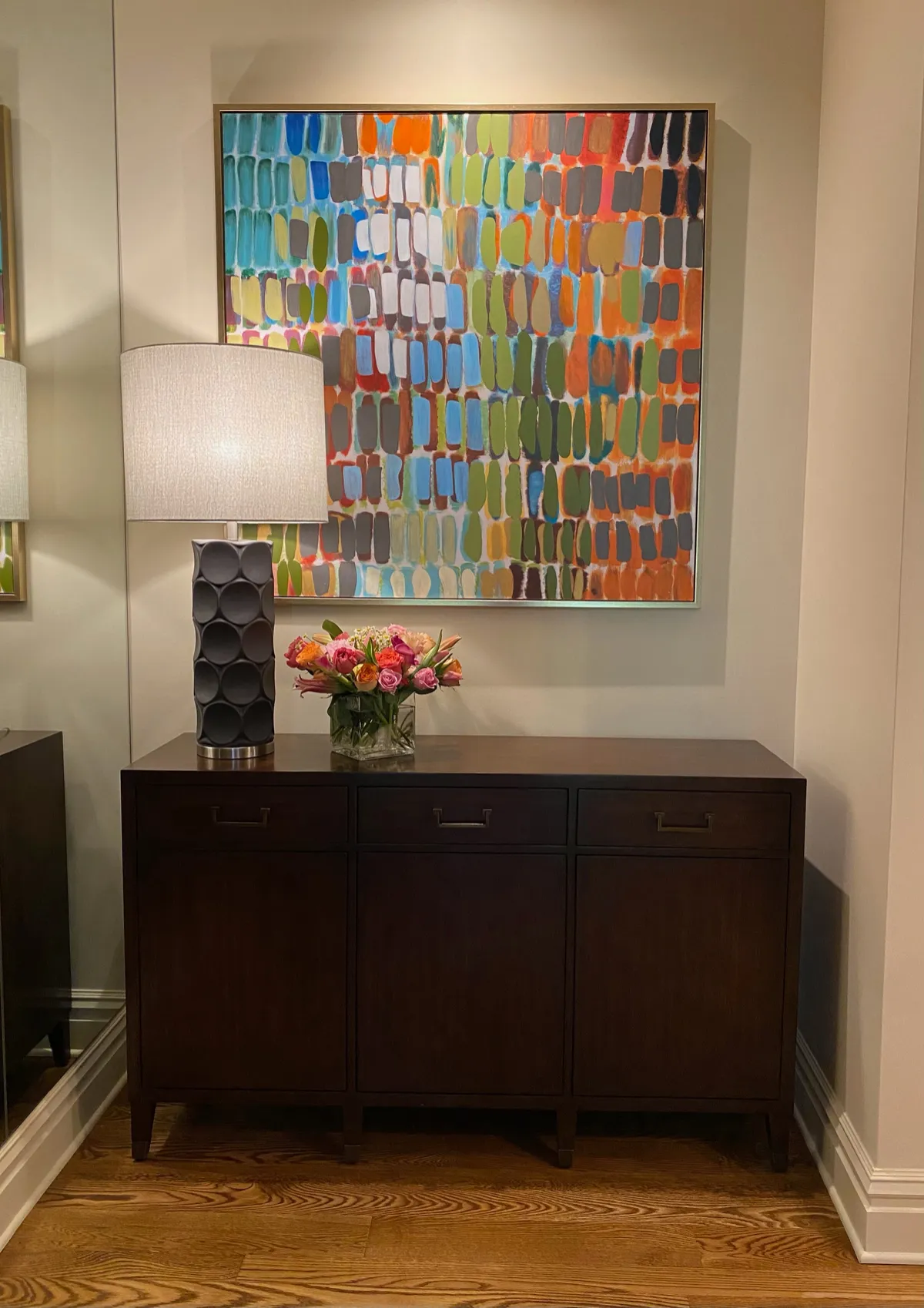 Colorful abstract grid painting above a dark wood sideboard