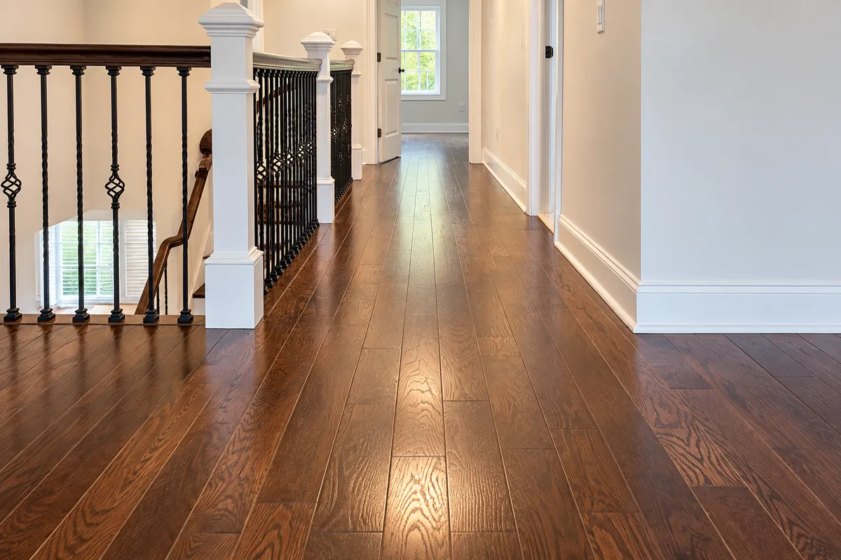 Glossy dark hardwood flooring beside a staircase with white railings