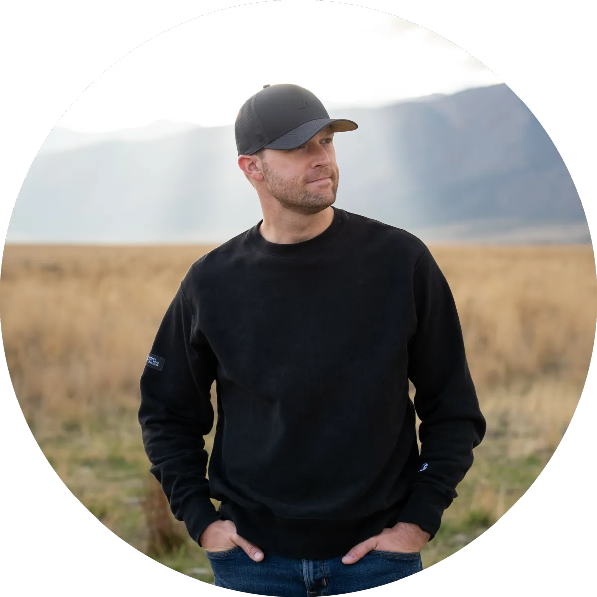 Thomas Nilsen standing outdoors in a grassy field with mountains in the background, representing intentional living, faith, men’s mental health, and steady personal growth.