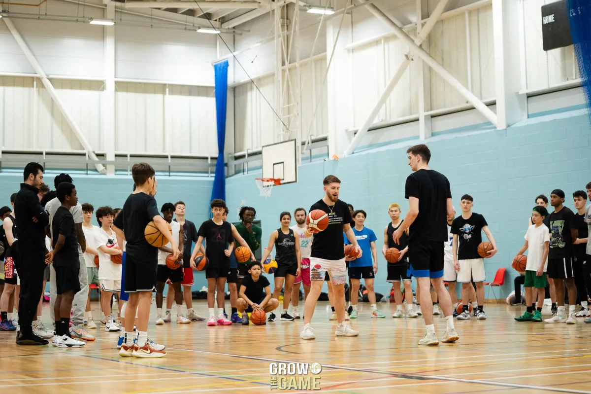 Large group of young basketball players participating in a high-energy skills clinic, led by expert trainers at a Grow the Game event, focusing on player development, teamwork, and advanced techniques.