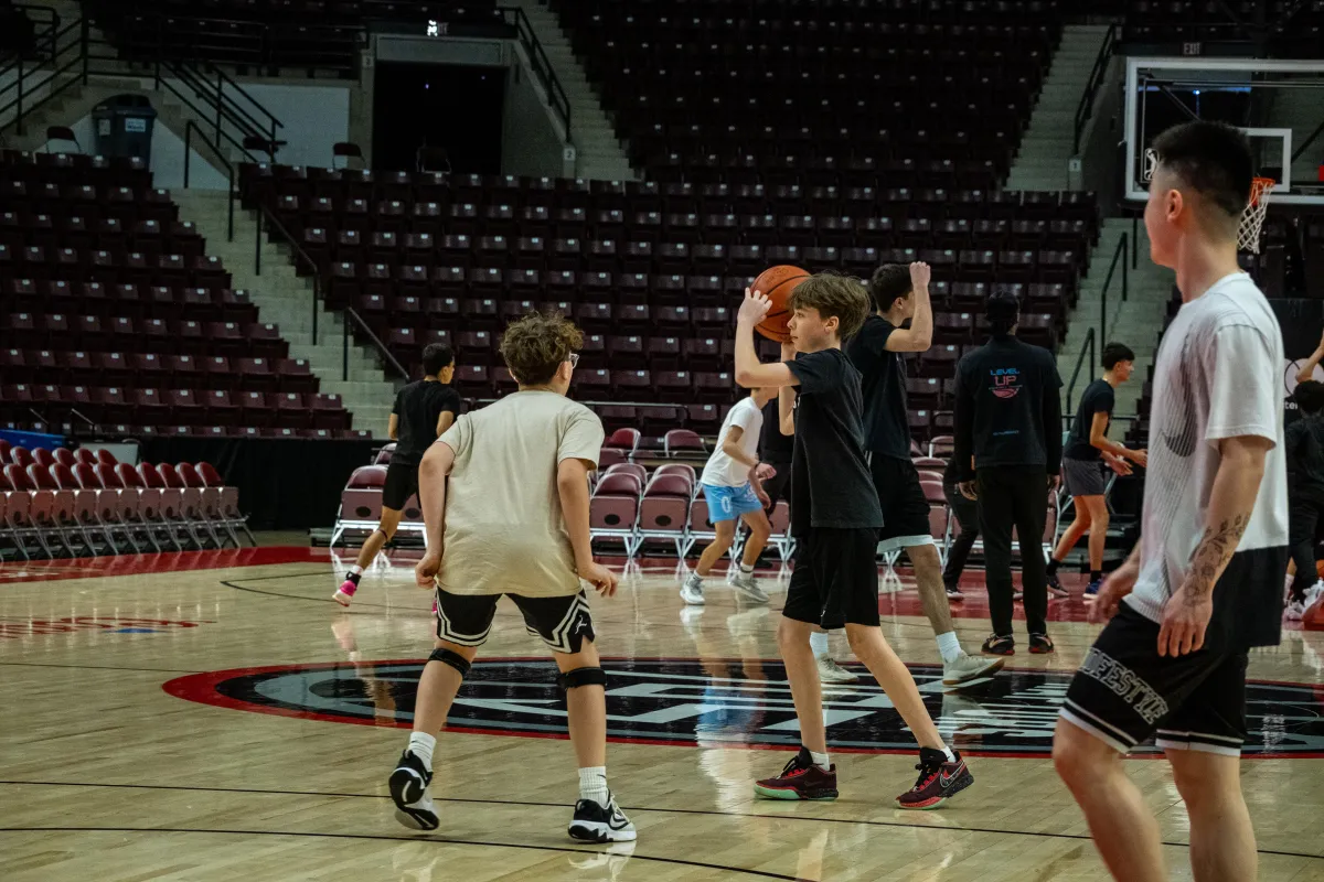 Young basketball players training in a gym, practicing skills and teamwork at an elite basketball training session in Oakville with By Any Means Toronto.