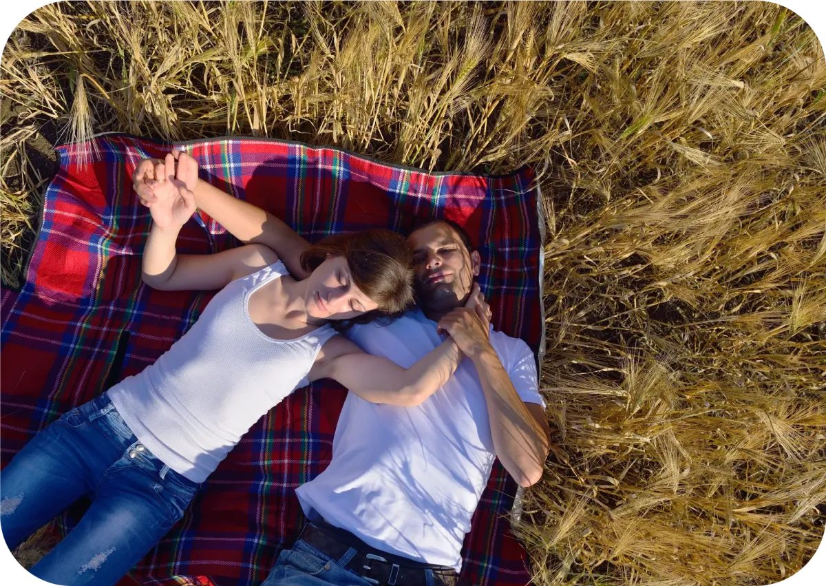  young couple cuddles on a blanket in a park while in love