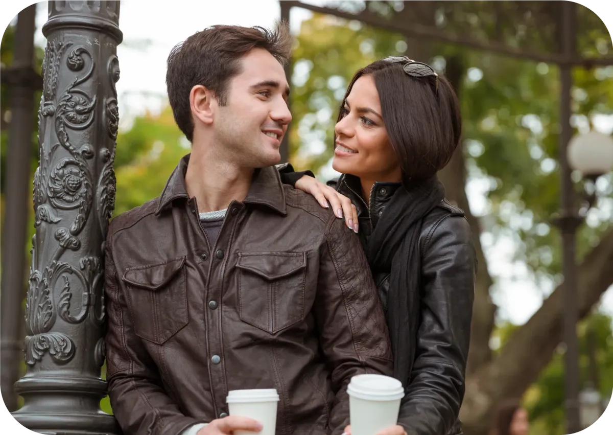 A girlfriend walks up behind her boyfriend and smiles