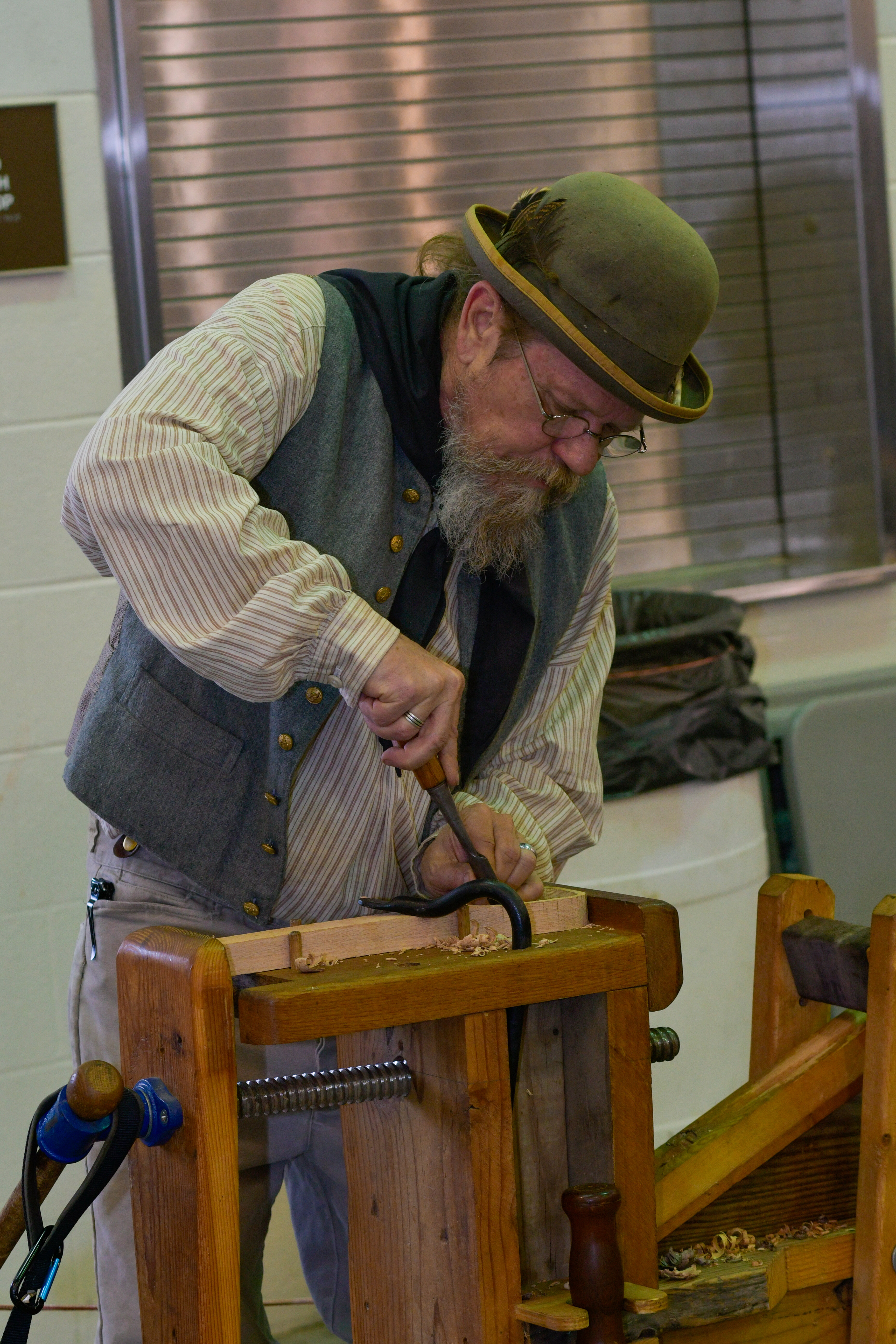 man carving a wooden spoon in old-fashioned clothing