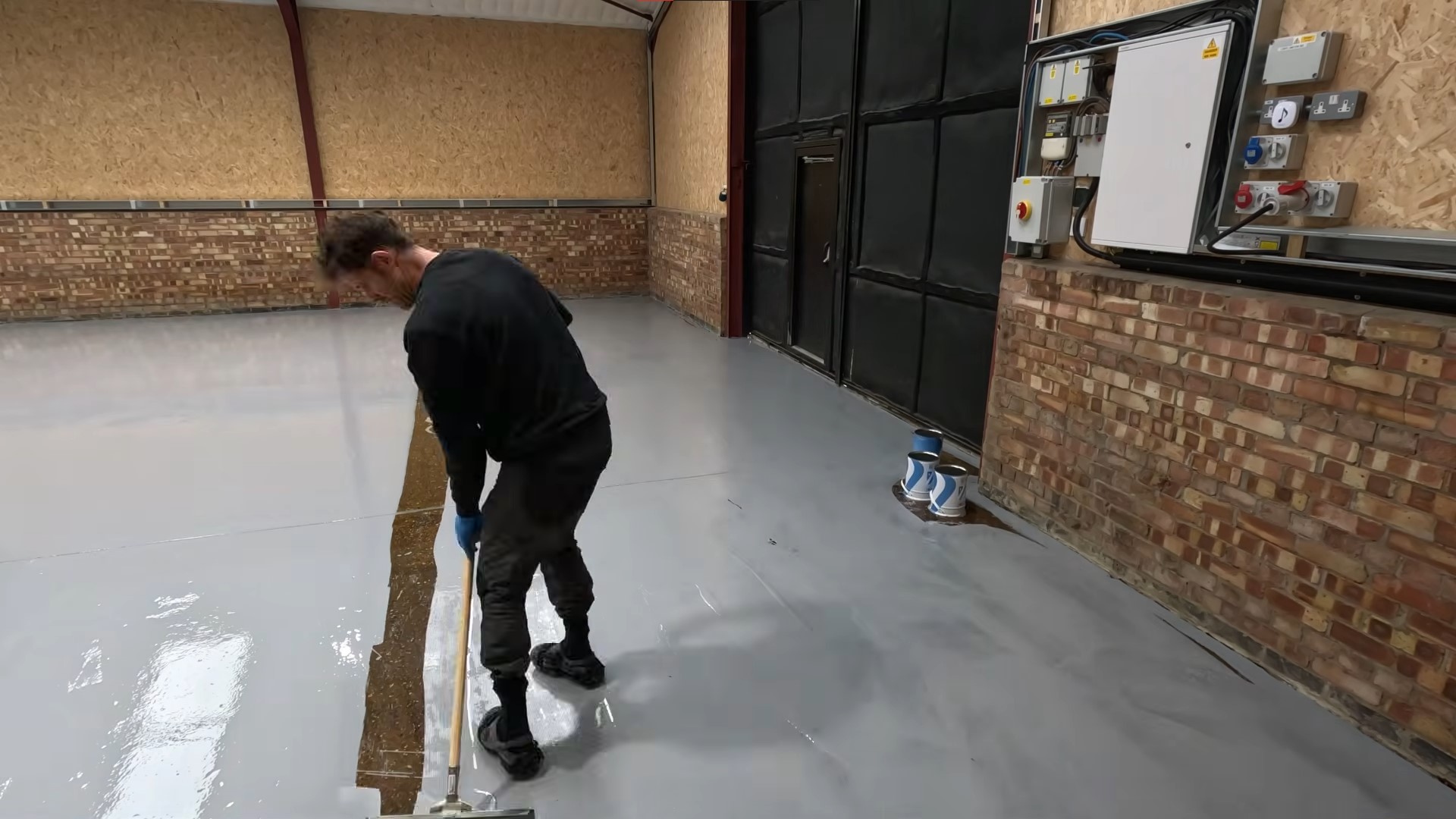 black shirt man applying plain grey base coat for his warehouse