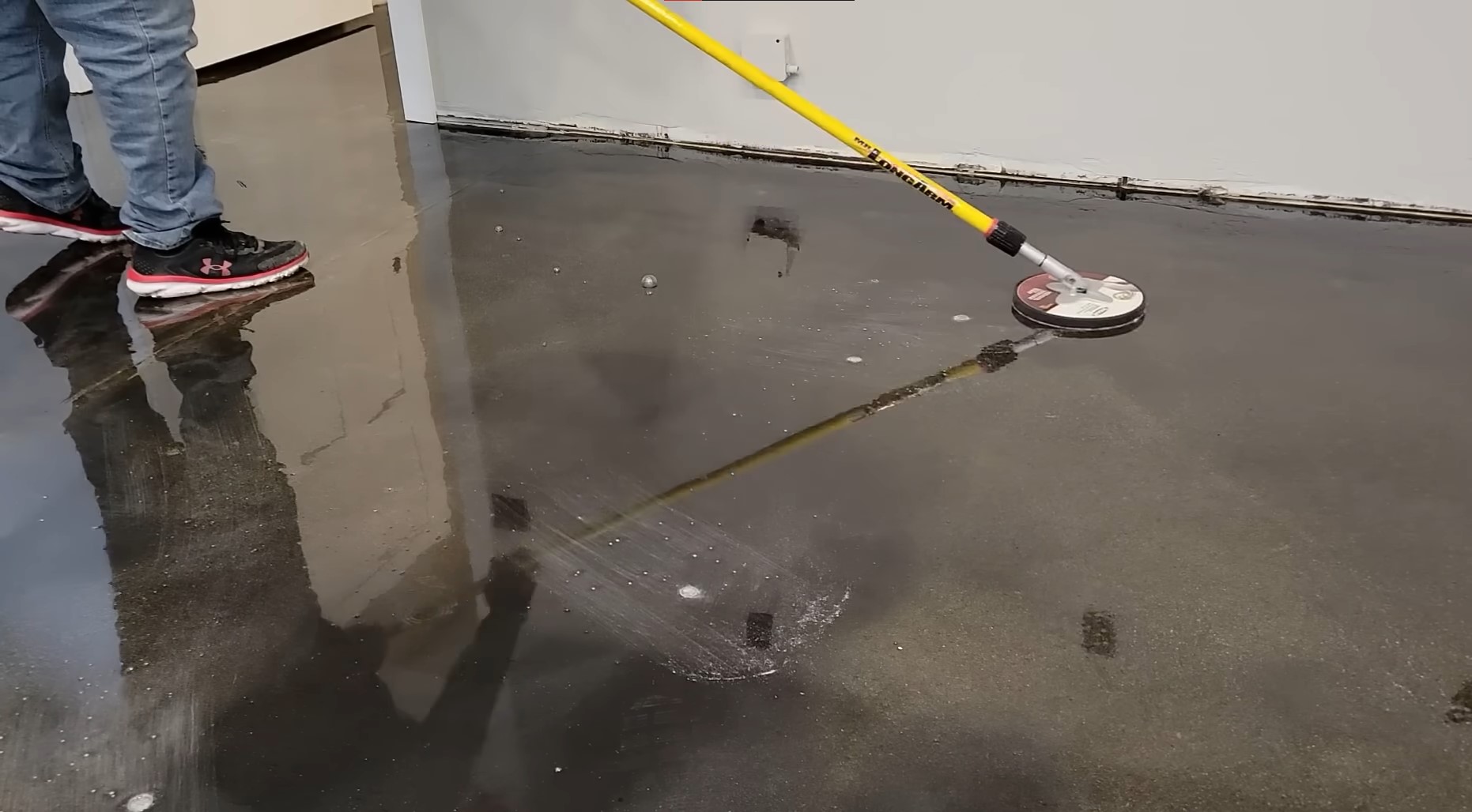 yellow car parkeconcrete floor with sealant coat being sanded with yellow sanderd in 4 car garage with epoxy flake floor