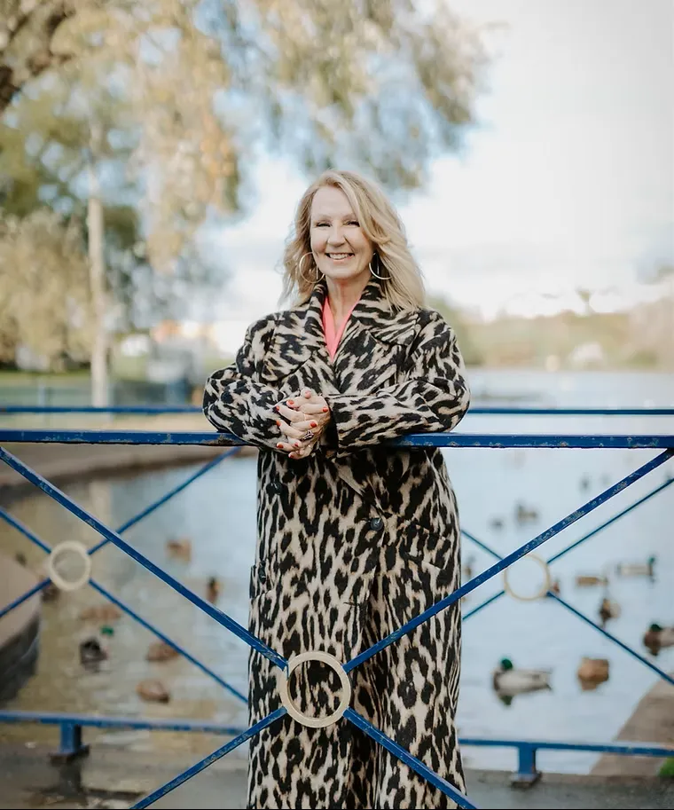 terri reynolds, founder coach and strategist standing in a inter coat by the river