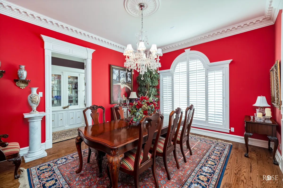 large dining room with attached butlers pantry, hardwood floors, crown moulding and plantation shutters
