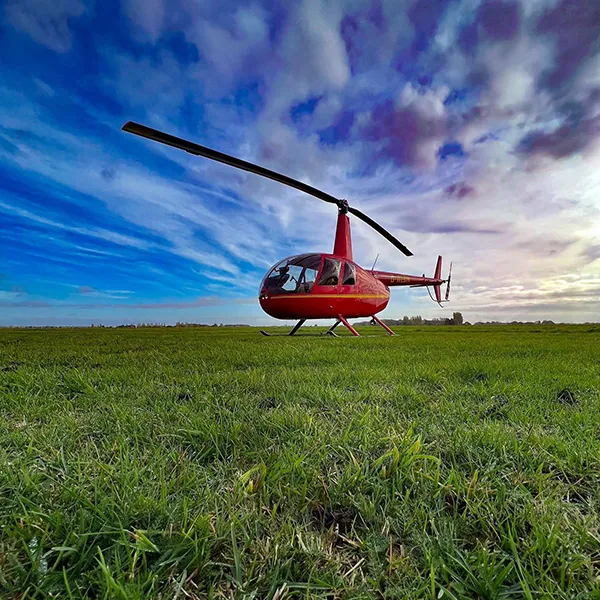 Yorkshire Helicopters R44 on the grass against blue sky