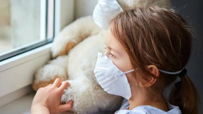 little girl indoors with mask on her face