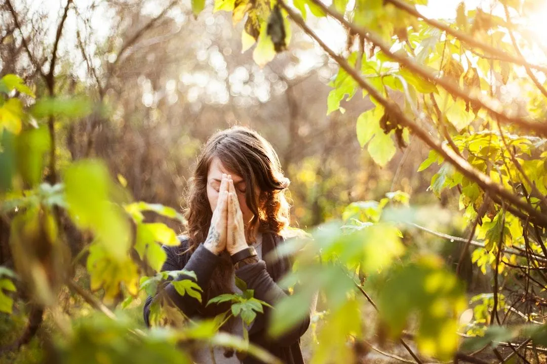 woman praying in the woods