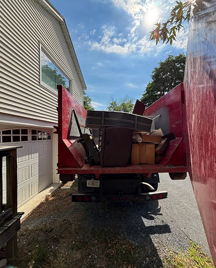Dirty D's junk removal truck loaded with furniture and debris in a residential driveway