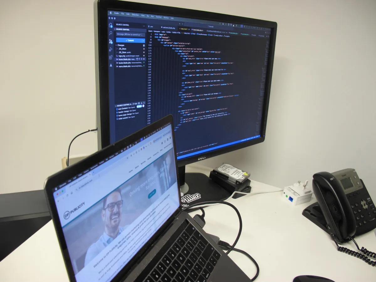 A laptop and computer monitor showing a website and coding.