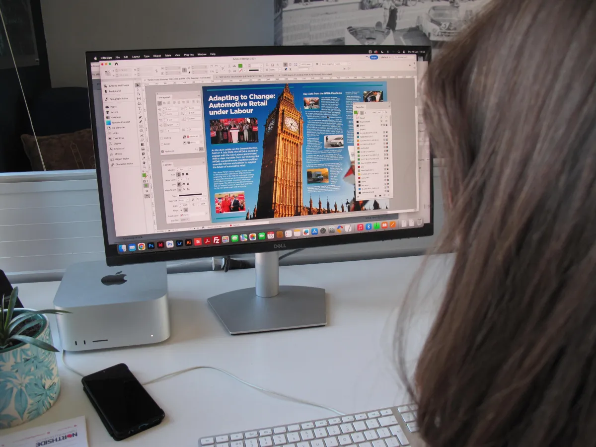 Computer monitor on an office desk showing artwork of Big Ben with editing software visible around the edges with mobile phone visible on the desk. 