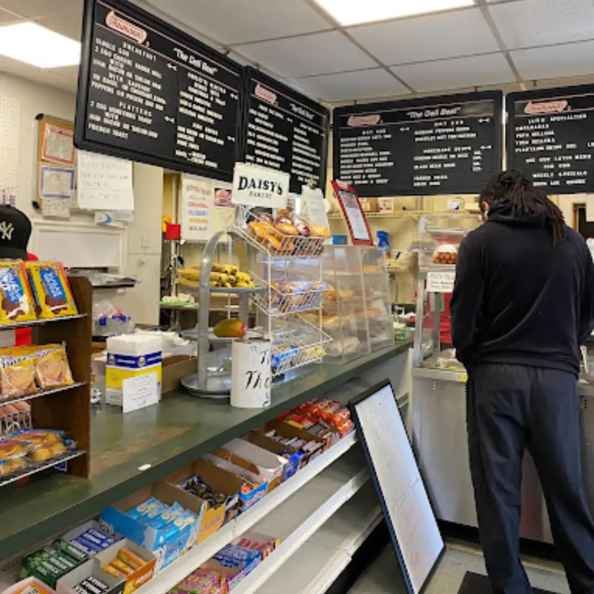 A wide-angle view of La Cocina’s deli interior in Fairfield, NJ, showing menu boards, fresh bread, and a welcoming atmosphere for customers.