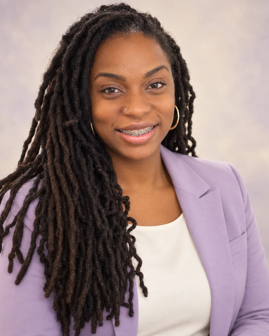 Portrait of Shidelle Watson, MSN, APRN, PMHNP-BC in a white coat over a black shirt with gold earrings