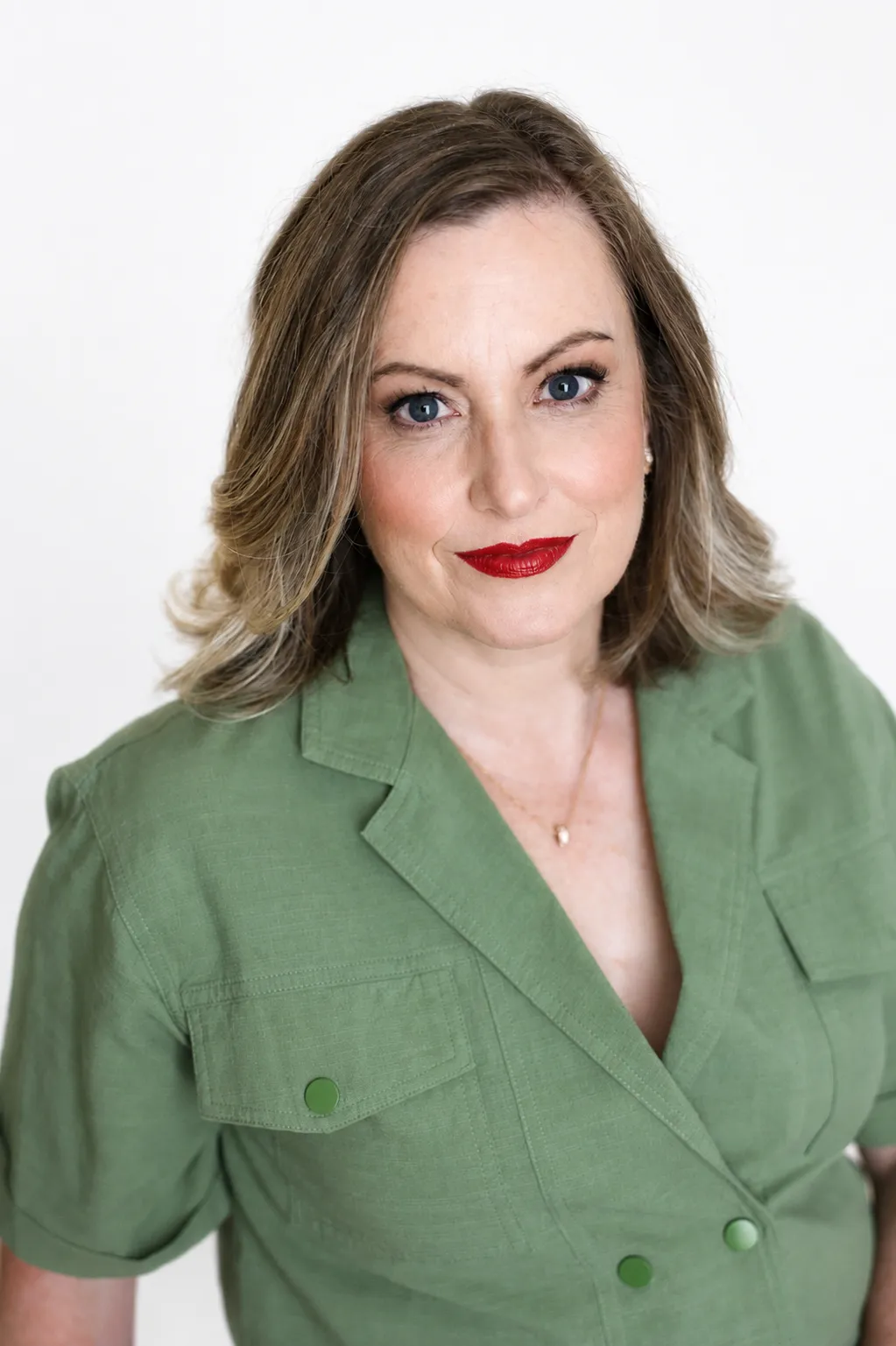 Professional warm portrait of Andrea looking at the camera wearing a deep green blazer