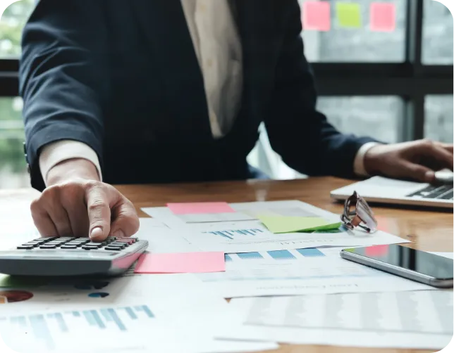 Professional analyzing business finances with a calculator and charts.
