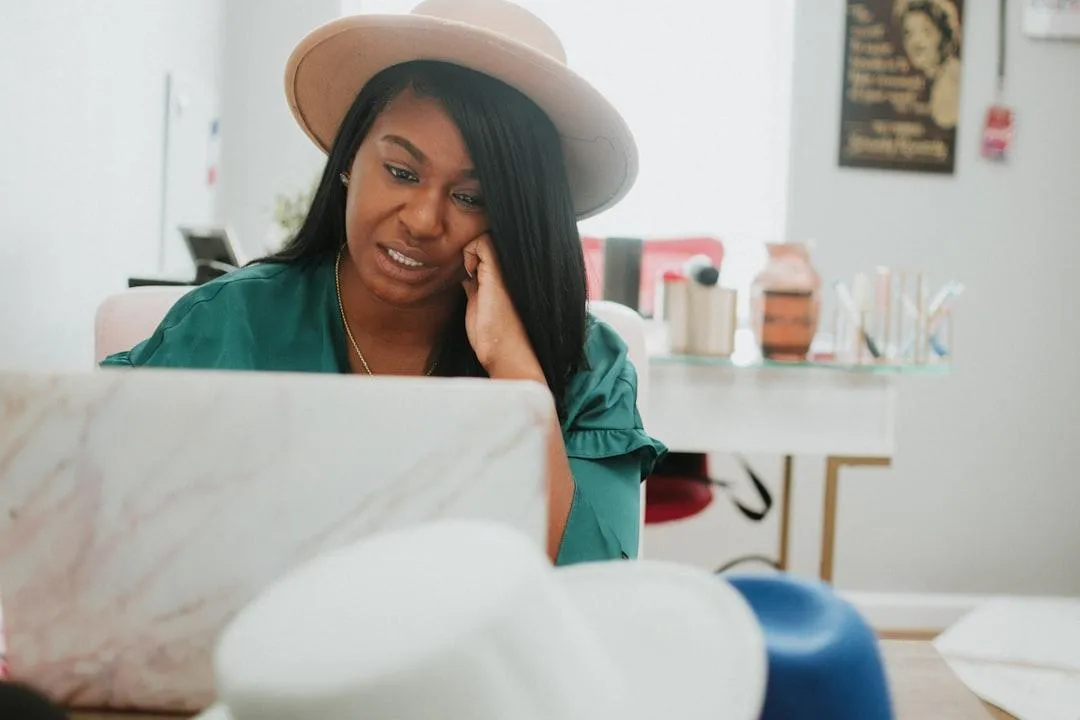 Woman looking stressed and overwhelmed while working on a laptop, symbolizing the feeling of being stuck and burnt out in business