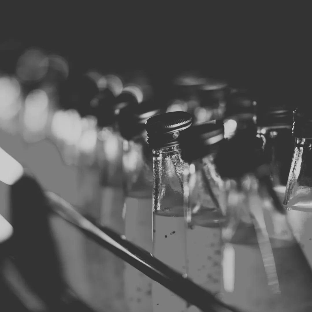 lose-up of non-alcoholic glass bottles with silver caps, reflecting light in a dimly lit setting, showcasing the intricate details and textures of the bottles.