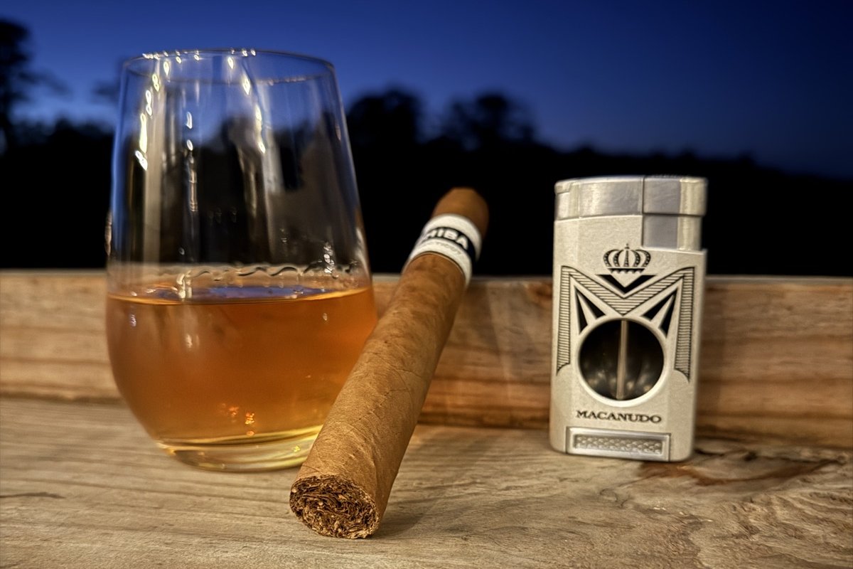 Cigar, glass of whiskey and cigar cutter on the deck rail at dusk, Uptown Tap & Cigar