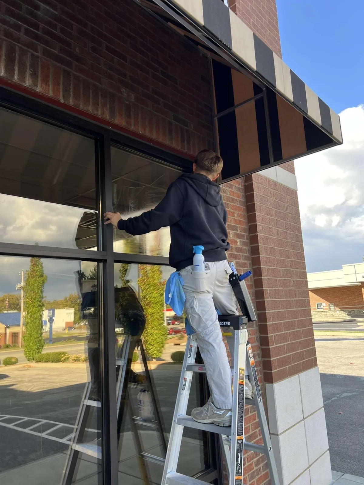 Professional window cleaner using squeegee on large glass window