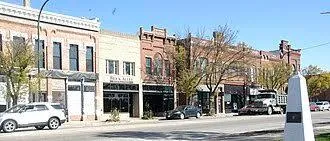 A downtown street lined with historic brick storefronts and parked cars in the Marion or Hiawatha area.