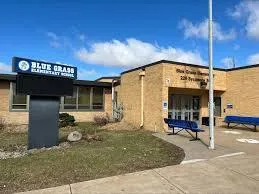 Exterior of a public building with a sign reading “Bettendorf City Hall,” surrounded by grass and a flagpole in front.