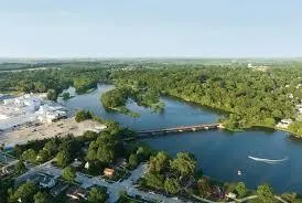 Aerial view of a river winding through a city surrounded by trees, bridges, and residential neighborhoods.