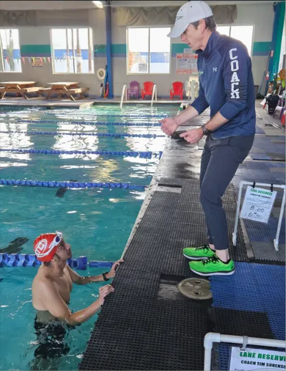 Coach Tim Sorensen talking with a swimmer at the pool edge