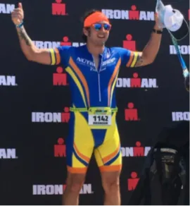 Brandon Pratt celebrating at an Ironman finish with arms raised