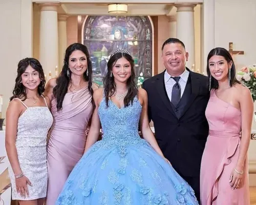 A quinceañera in a lavender ball gown walks hand in hand with her parents during the celebration, surrounded by guests in formal attire.