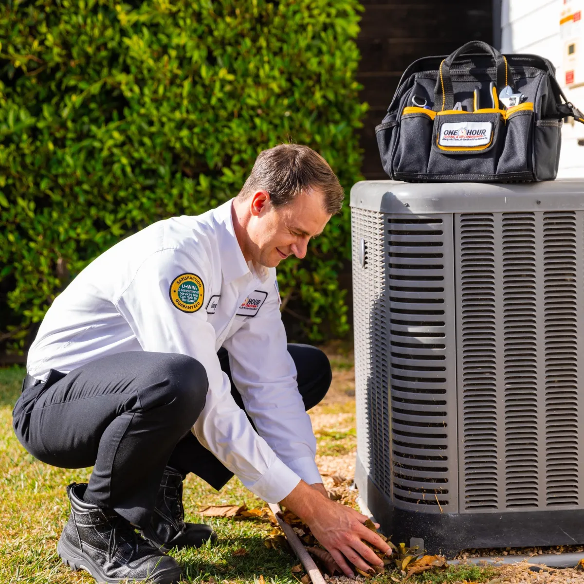 One Hour Heating & Air Conditioning technician performing outdoor HVAC unit maintenance in an Atlanta backyard
