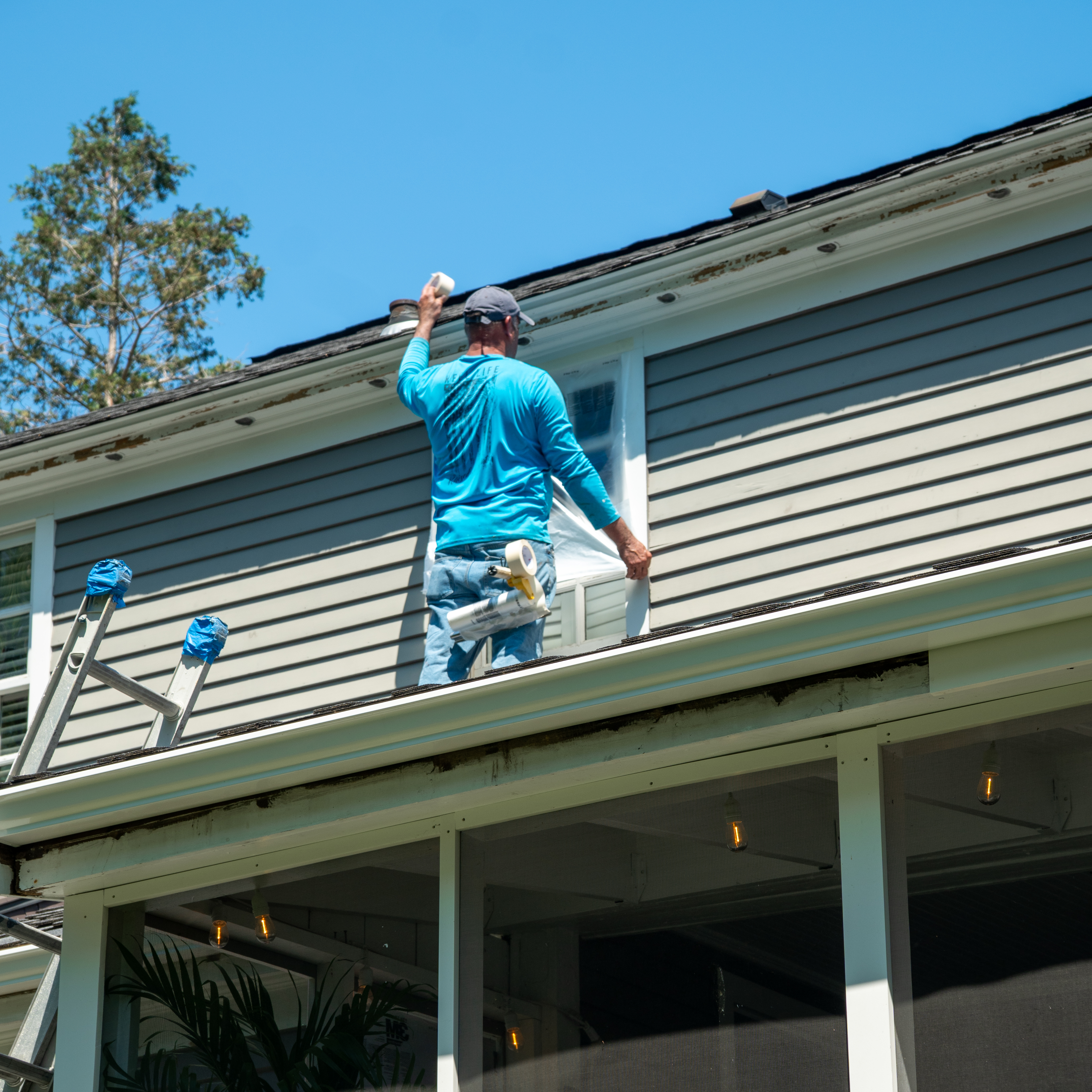 M&C Painting covering windows before an exterior paint job