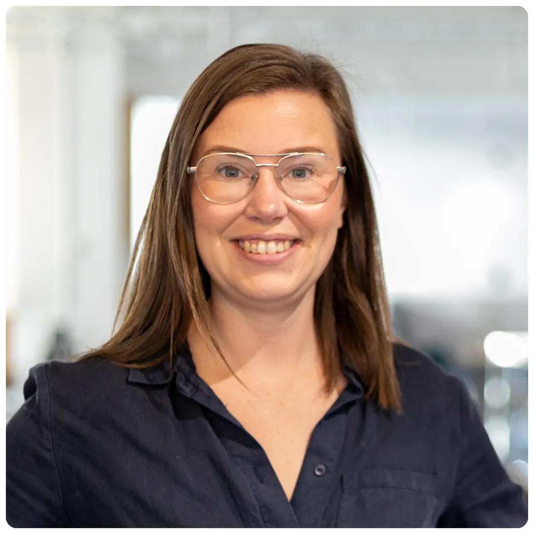 Närbild på Hanna Rudolfsson på Företagarbyrån. Hon har en svart skjorta på sig, glasögon med ljusa bågar och ler mot kameran.