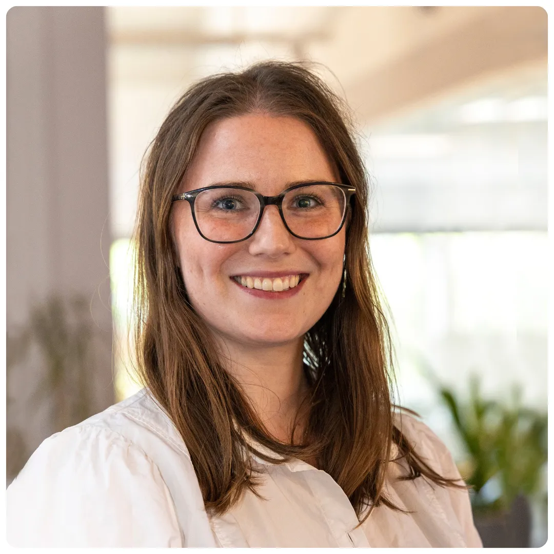 Emilia Sandell är företagsutvecklare på Företagarbryrån och hon ler mot kameran och har en vit blus på sig och glasögon med mörka bågar. I bakgrunden syns gröna löv från två stora växter och ljuset från ett stort fönster