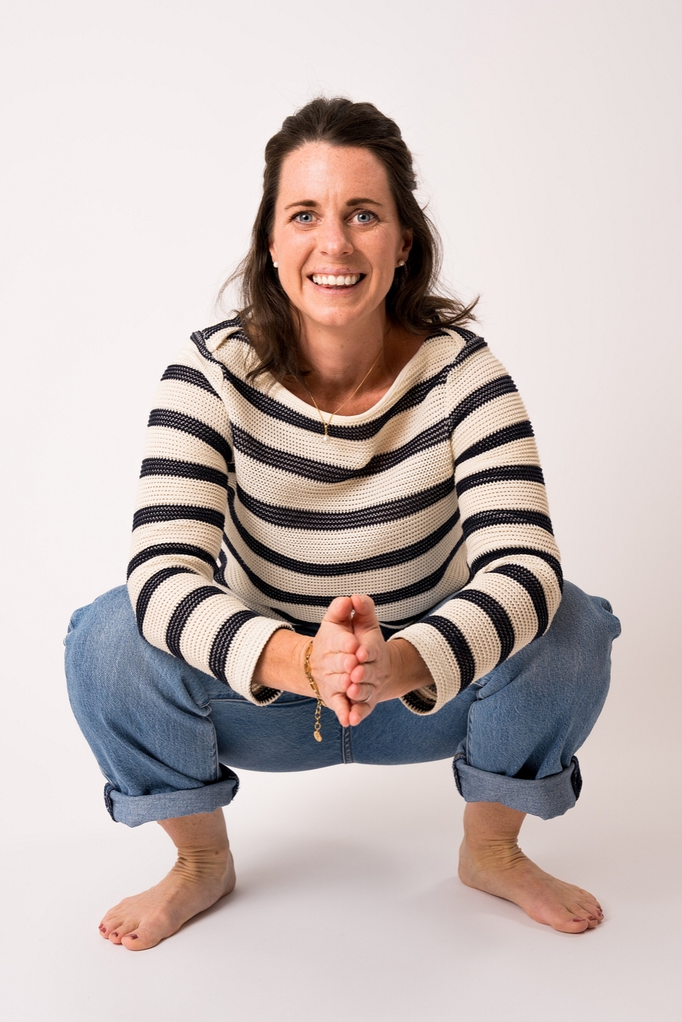 Onlineföretagare Emelie Ritter sitter på huk med händerna mot varandra framför sig. Hon ler mot kameran och har en vit-svart randig tröja på sig