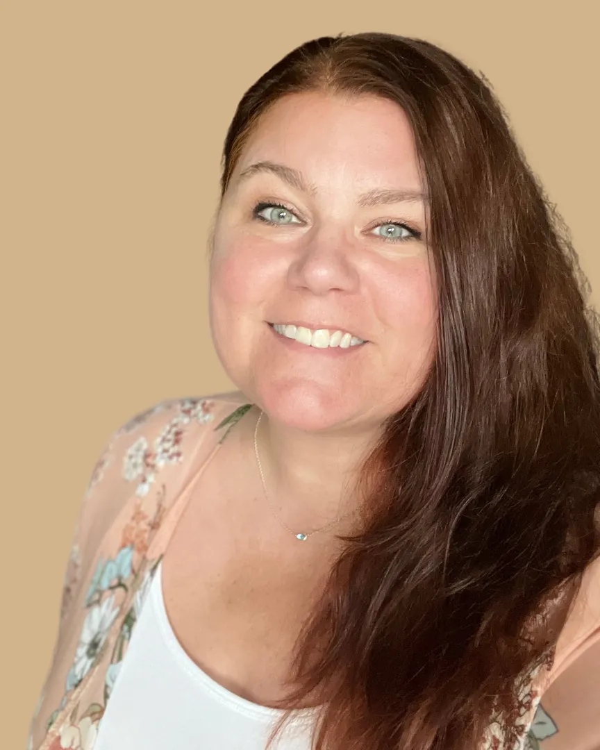 onlineföretagaren Veronica Sund Holmlund från Jag är sund står mot en gulbeige bakgrund och ler mot kameran. Hon har en vit tröja och en blommig blus över.