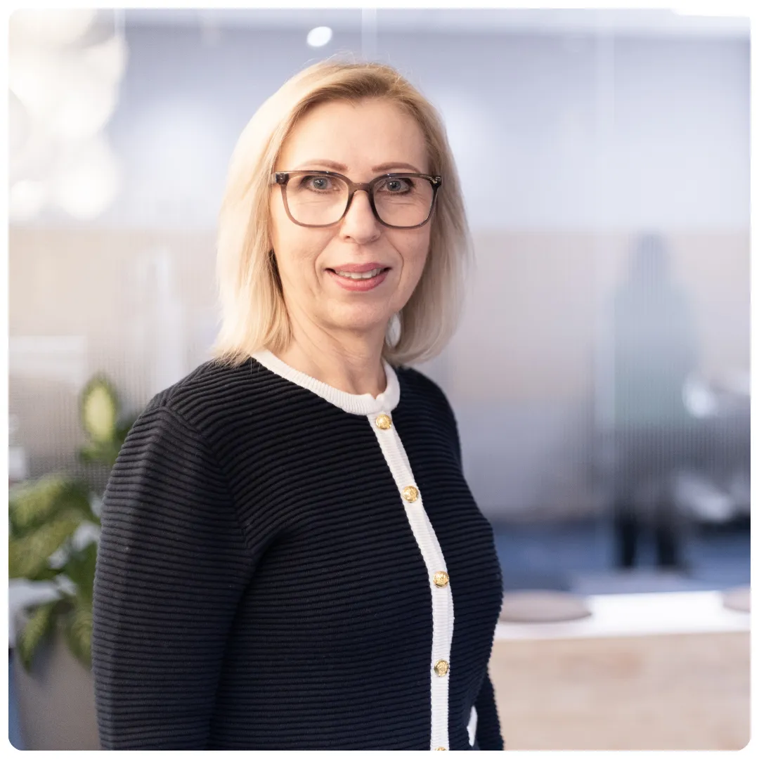 Anna-Lena Jansson på Företagarbyrån har en gul tröja på sig och glasögon med mörka bågar. Hon står i ett ljust öppet kontorslandskap och ler mot kameran.