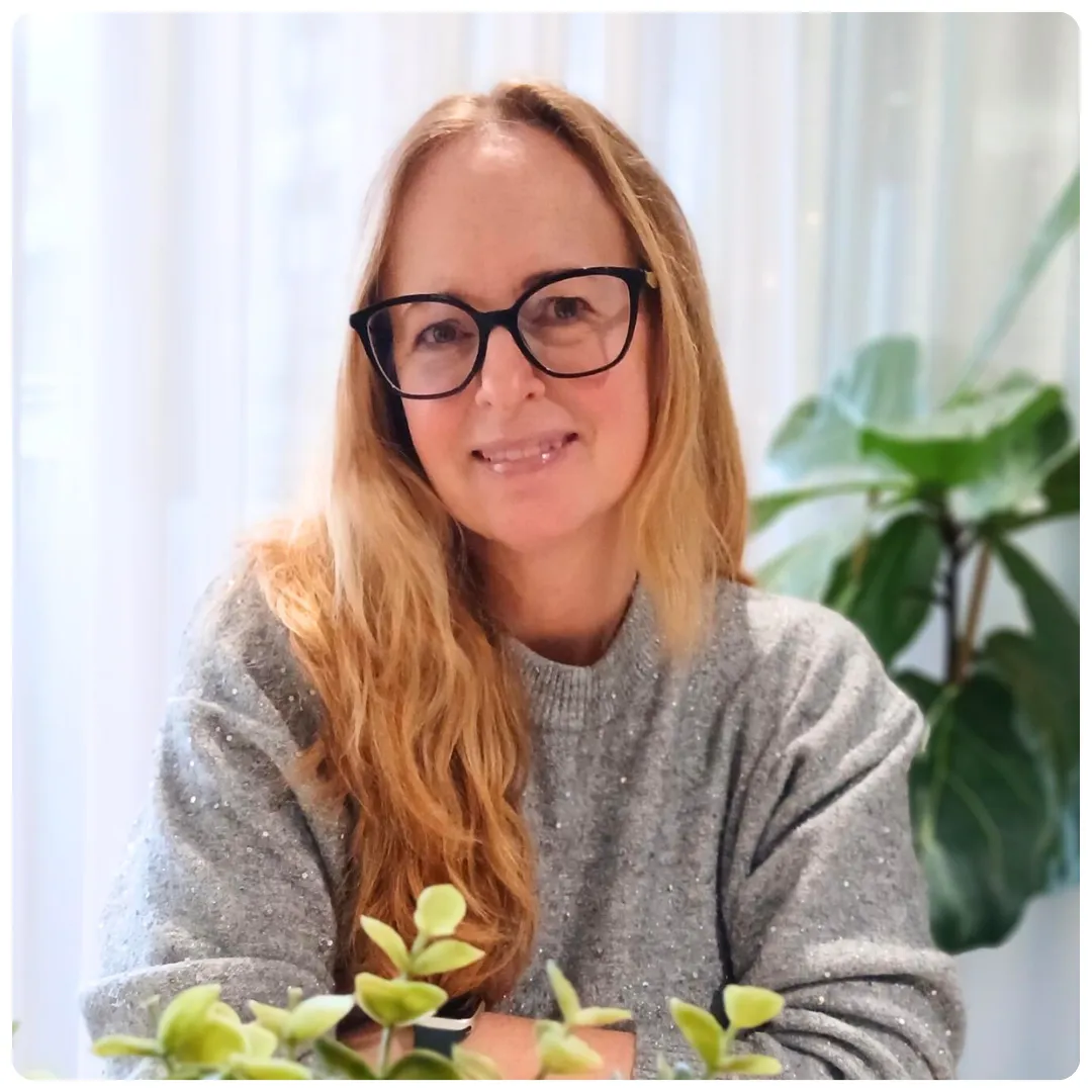 Jenny Ohlsson på Företagarbyrån står i ett ljust öppet kontorslandskap och ler mot kameran. Hon har en ljusrosa tröja och glasögon med mörka bågar.