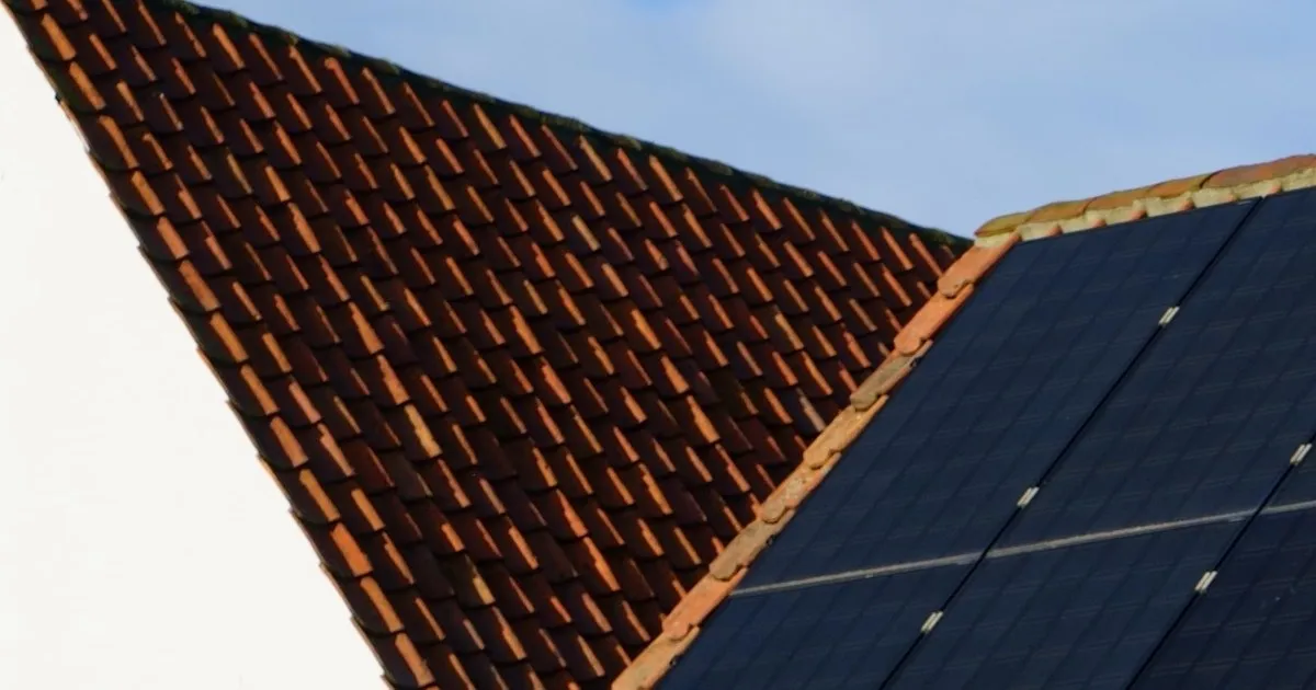 Solar panels on a tiled house roof under a blue sky