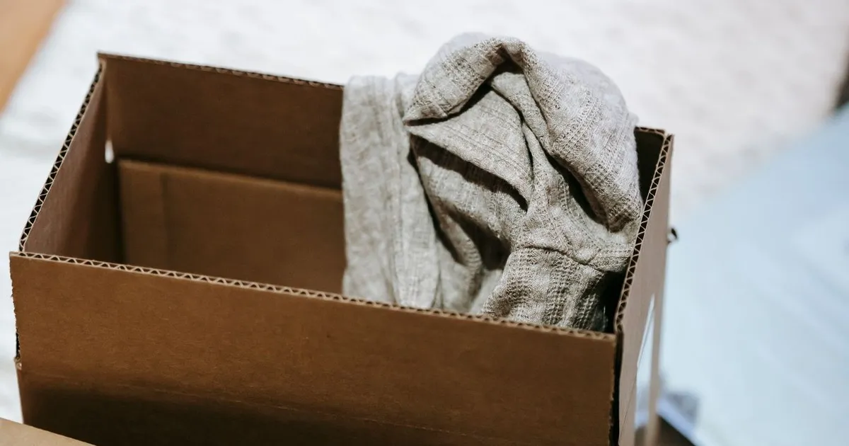 An open cardboard moving box with a folded gray sweater inside