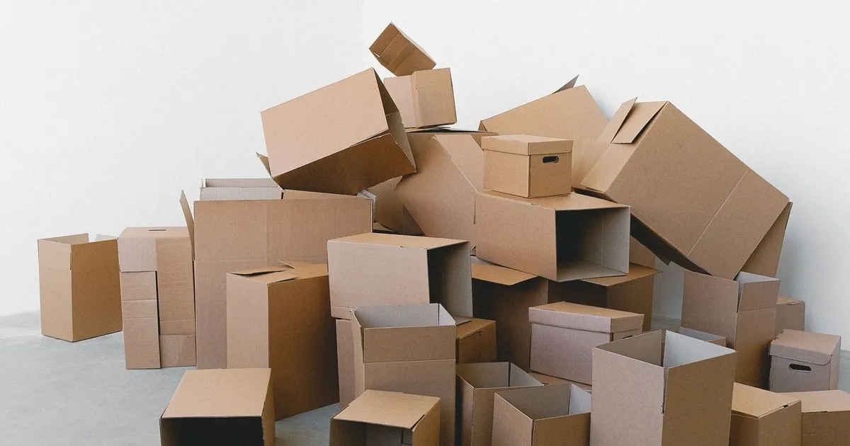 Stacks of empty cardboard moving boxes piled in a bright white room