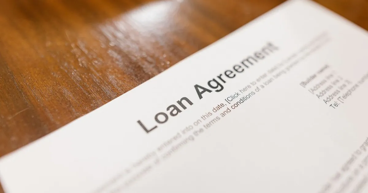 Printed loan agreement form lying on a wooden table