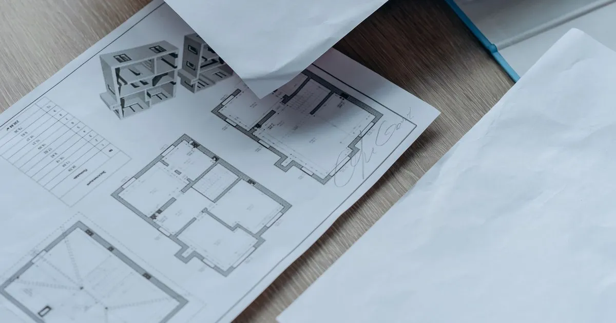 House floor plans and loose paperwork spread on a wooden table